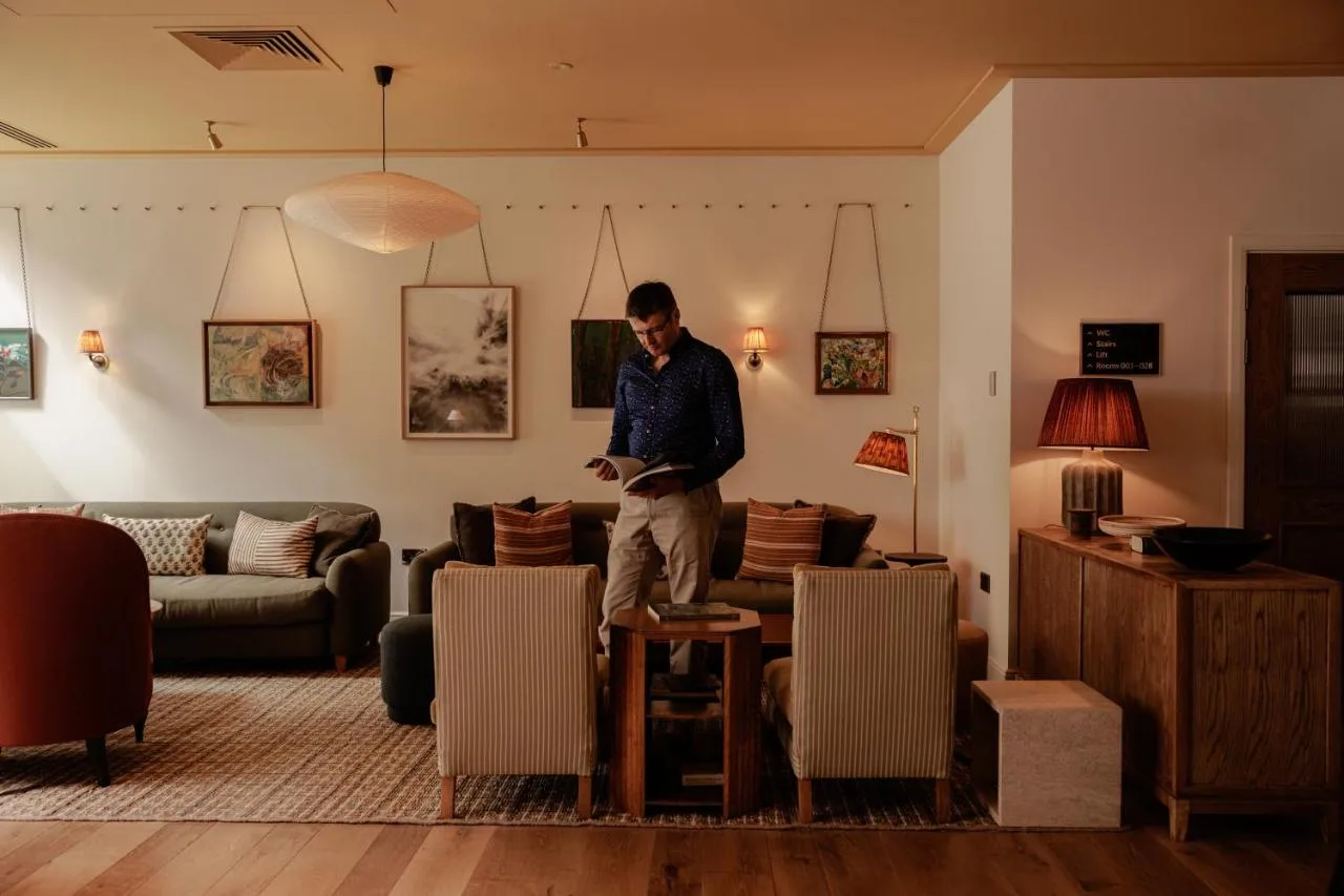 a man standing in a living room looking at his phone at Wilde Cambridge City Centre in Cambridge