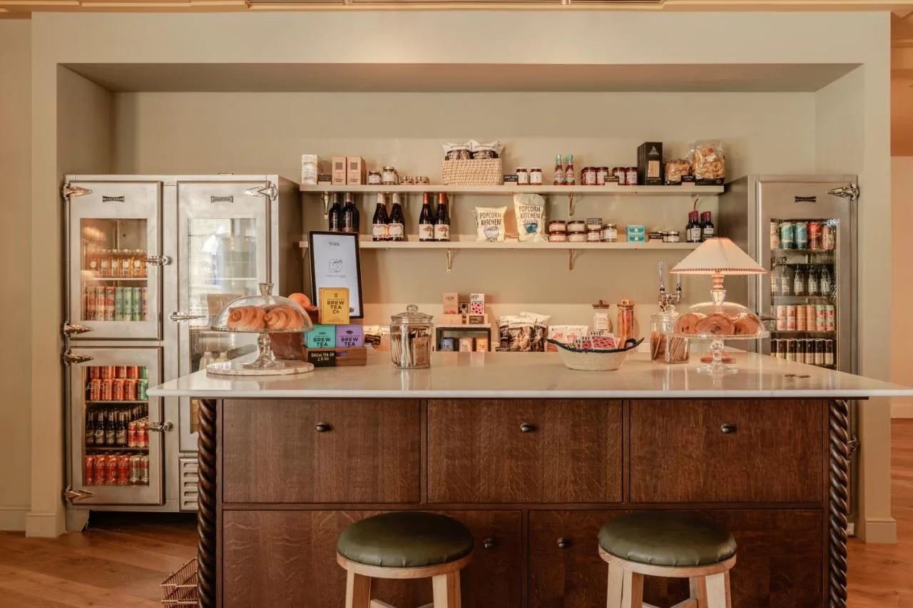 a kitchen with a counter with stools and a refrigerator at Wilde Cambridge City Centre in Cambridge